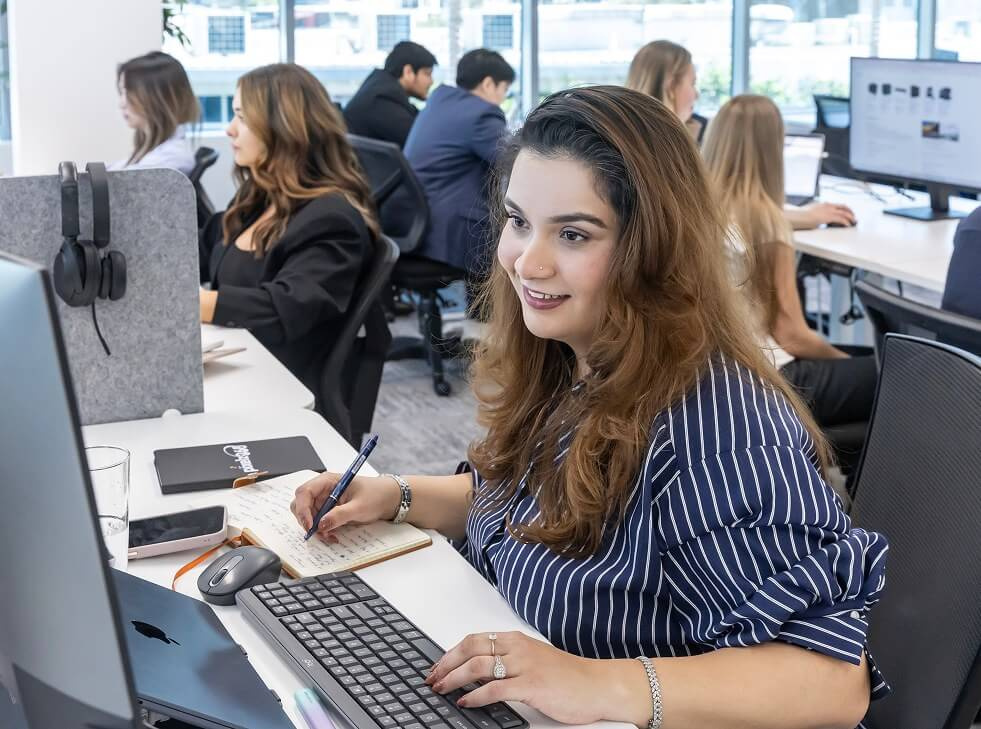 A team member taking handwritten notes at her keyboard