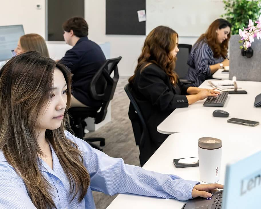 A team member focused on her screen with colleagues working behind her