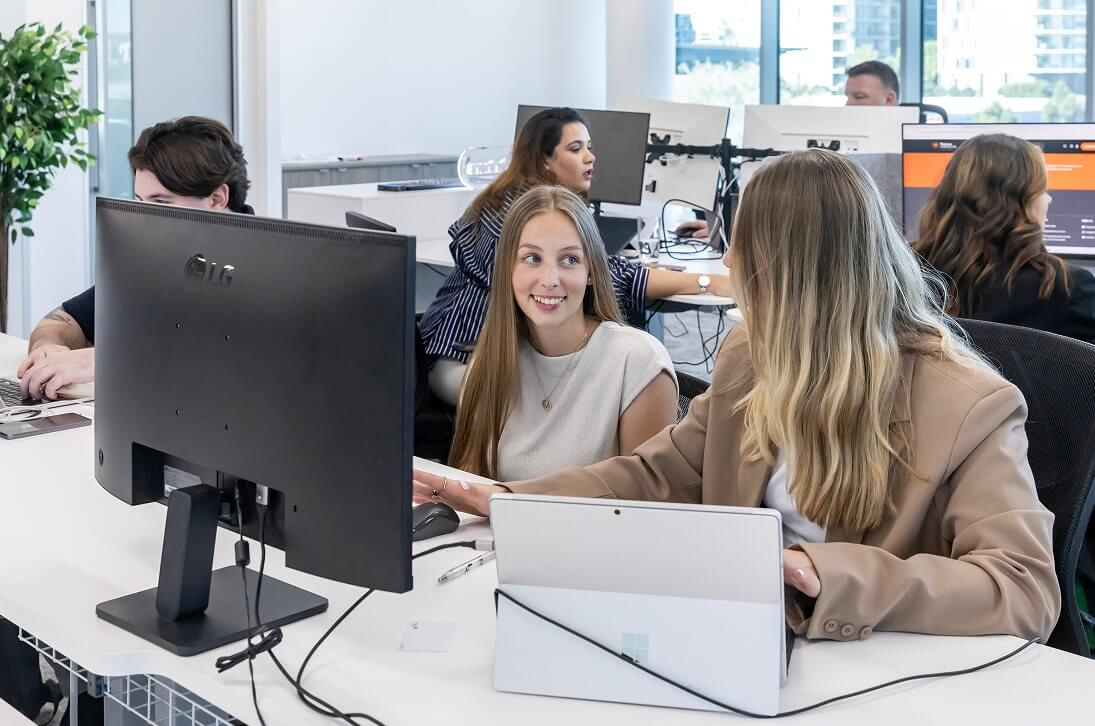 Two team members chatting across their desks in the open-plan office